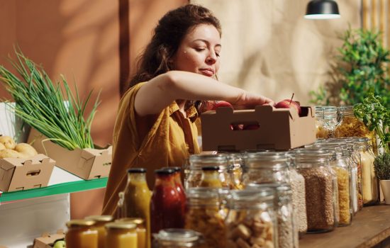 Woman adding eco store apples to basket Vegan woman in specialty zero waste supermarket counting apples, adding them to shopping basket. Client in local neighborhood grocery shop picking freshly harvested fruits