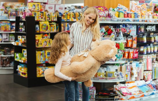 Happy mother and daughter Happy mother and daughter standing at the supermarket and holding big teddy bear